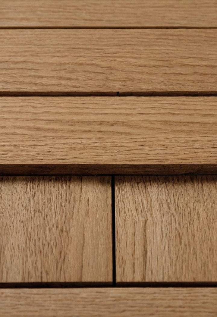 Three planks of oak flooring of different thicknesses stacked in a step on a white surface, showing their end grain.